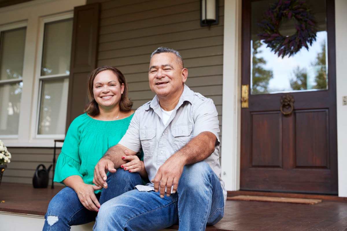 A couple sitting on the porch steps of their house