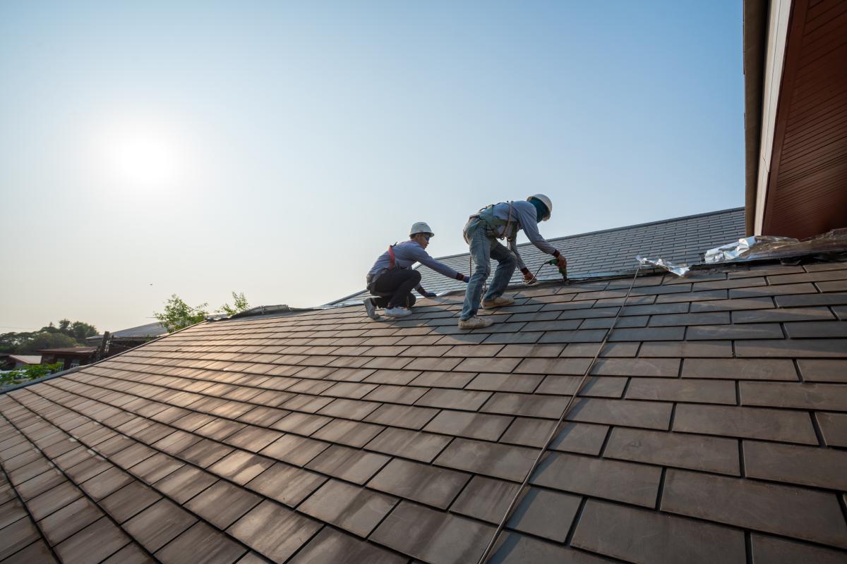 Two roofers replacing a roof with like kind and quality shingles